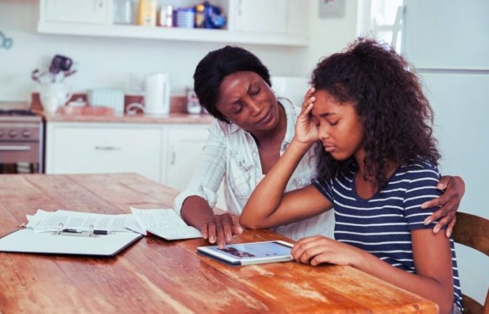 A mother helping her daughter study at the kitchen table